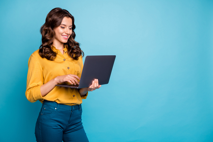 Portrait of her she nice attractive lovely cheerful cheery wavy-haired girl holding in hands, laptop creating presentation isolated over bright vivid shine vibrant green blue turquoise color background