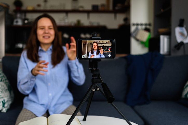 Woman in shirt Recording video at home for her video blog. Using smartphone