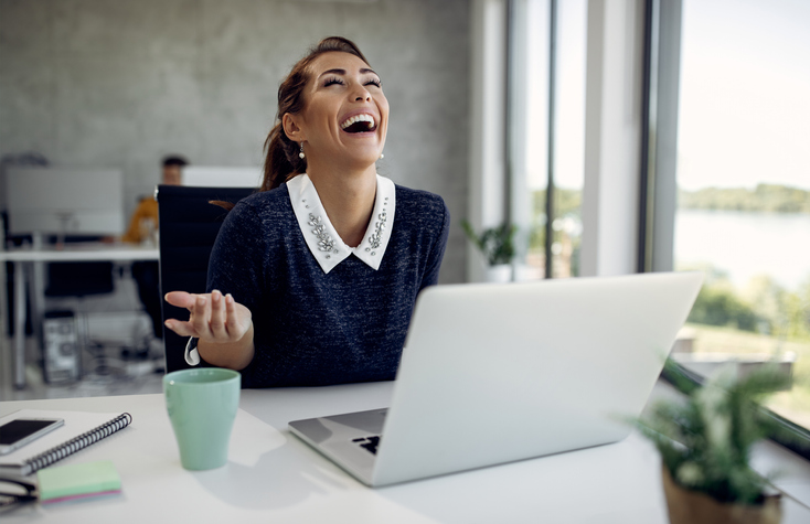 Young happy businesswoman laughing while having video call over laptop in the office.