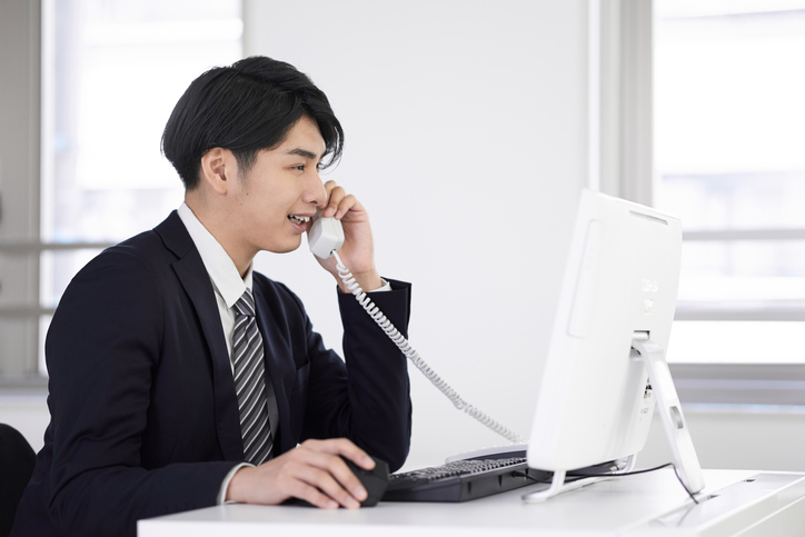 A Japanese male businessman answering the phone with a smile on his face