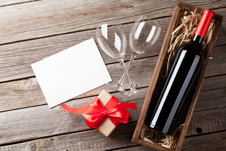 Valentines day greeting card. Red wine and gift box on wooden table. Top view with copy space