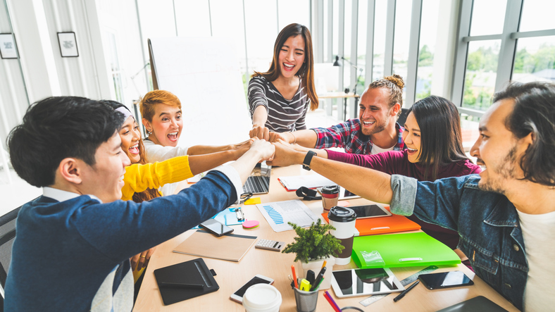 Multiethnic diverse group office coworker, business partner join hands by fist bump in modern creative office. Colleague partnership teamwork, startup company, or project achievement celebrate concept
