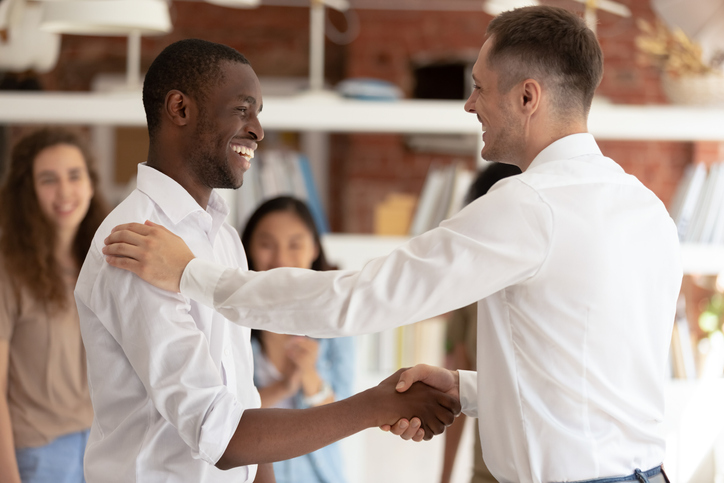 Caucasian executive boss handshaking promoting successful happy african black worker expressing gratitude praising shaking hand appreciating for good work, reward recognition acknowledgement concept