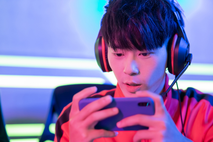Close Up of young asian teenage cyber sport gamer play mobile game by smartphone on eSport tournament