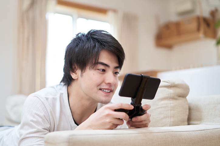 Asian man playing a smartphone game in the room