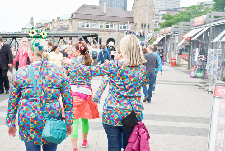 A group of female revellers (in colourful attire) walk towards a street party (festival parade) in Hamburg, Germany.